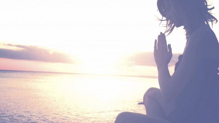 Woman meditating beach sunset
