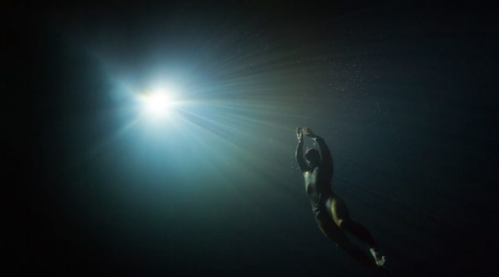 Free diver swimming to the light